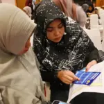 Pelaku UMKM memperhatikan brosur fasilitas kredit di bank. (© bmzIMAGES/basri marzuki)