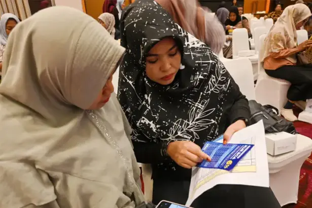 Pelaku UMKM memperhatikan brosur fasilitas kredit di bank. (© bmzIMAGES/basri marzuki)