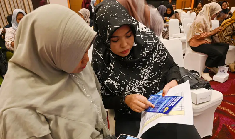 Pelaku UMKM memperhatikan brosur fasilitas kredit di bank. (© bmzIMAGES/basri marzuki)