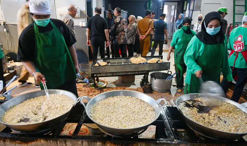 Pekerja menggoreng bawang di salah satu sentra produksi bawang goreng di Palu. (© bmzIMAGES/basri marzuki)