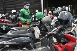 Seorang pengemudi ojek online memarkir sepeda motornya di tempat parkir kendaraan di Palu, Sulawesi Tengah, Sabtu (6/9/2025). (©bmzIMAGES/basri marzuki)