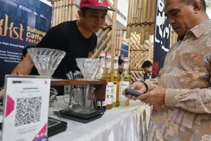 Warga menyiapkan gadgetnya untuk pembayaran melalui QRIS di salah satu outlet kopi di Palu, Sabtu (18/10/2025). (© bmzIMAGES/Basri Marzuki)